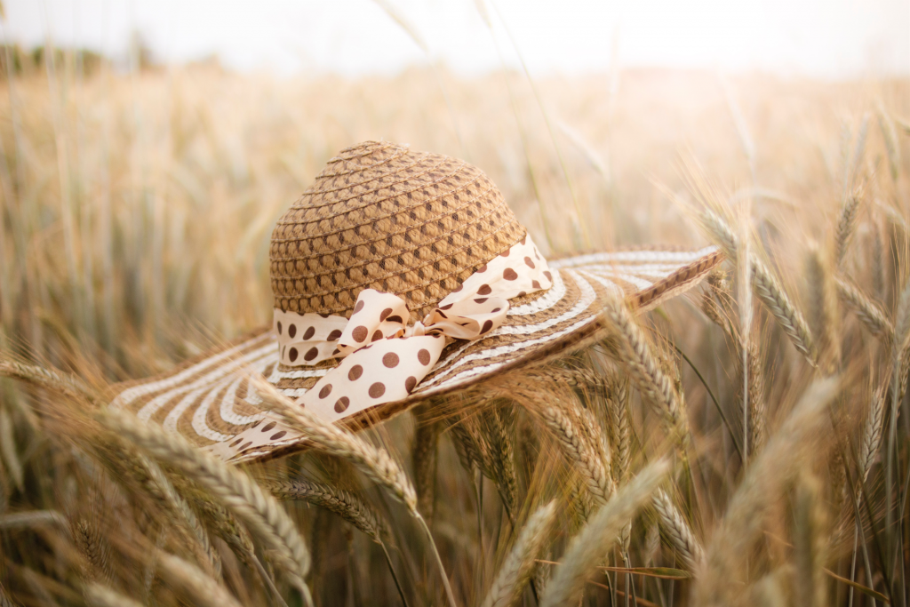 Straw hat laying on top of wheat field with sunlight in background