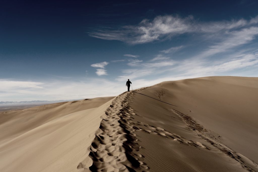 person walking uphill in deep sand 