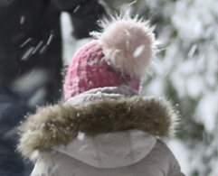 Little girl wearing winter jacket and pink beanie hat with light pink pom pom