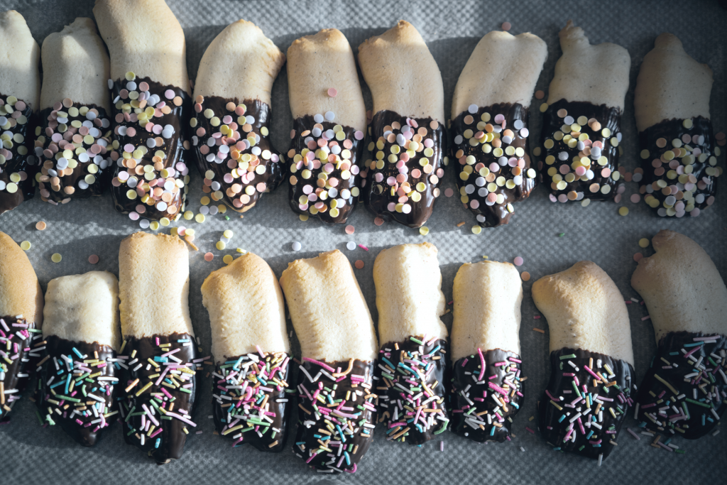 Christmas cookies dipped in dark chocolate and covered with colorful sprinkles