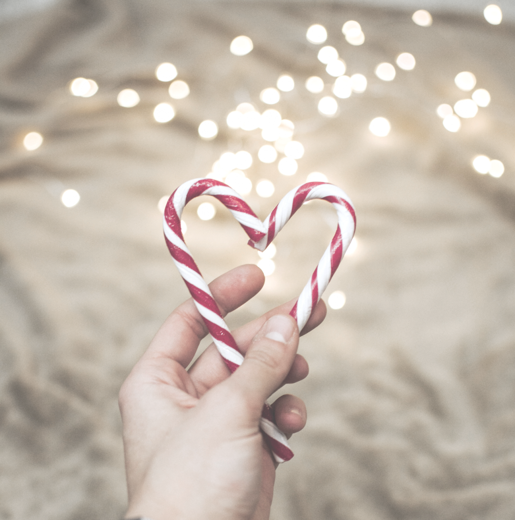 Close up of candy cane heart with gold lights in background