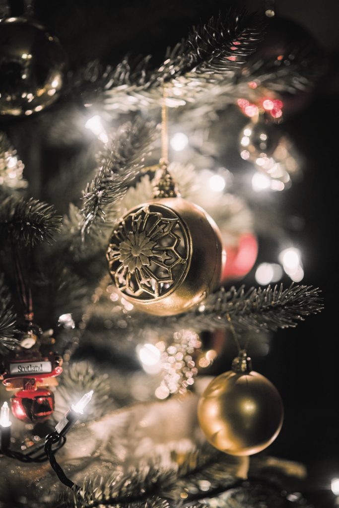 Close up of Christmas ornaments on tree with blurred white light