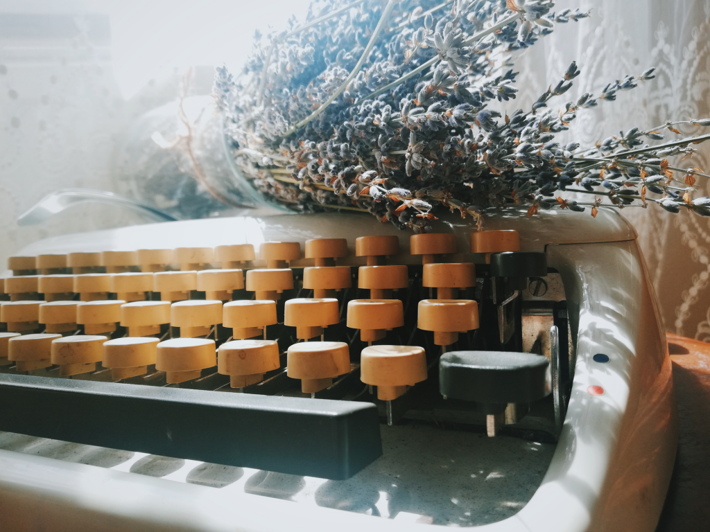 Close up image of old fashioned typewriter with the tan colored keys and bouquet of lavender laying on top