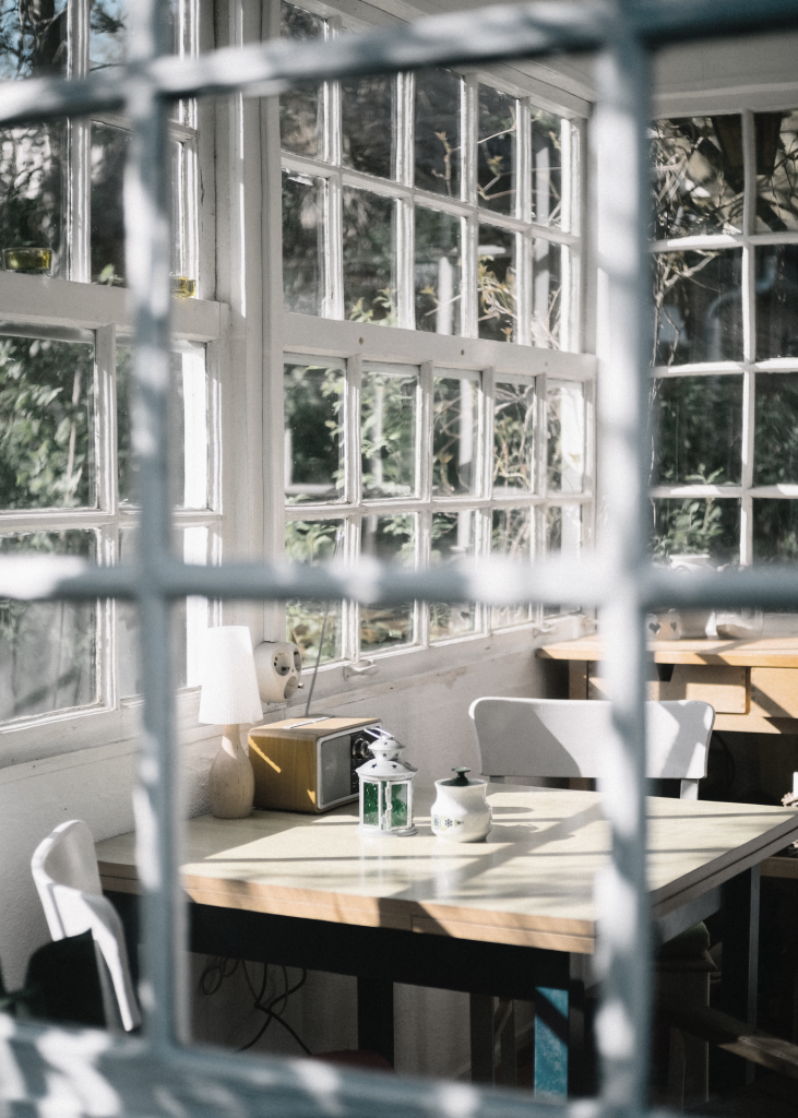 Looking through a paned window into a sunroom with a table and chairs