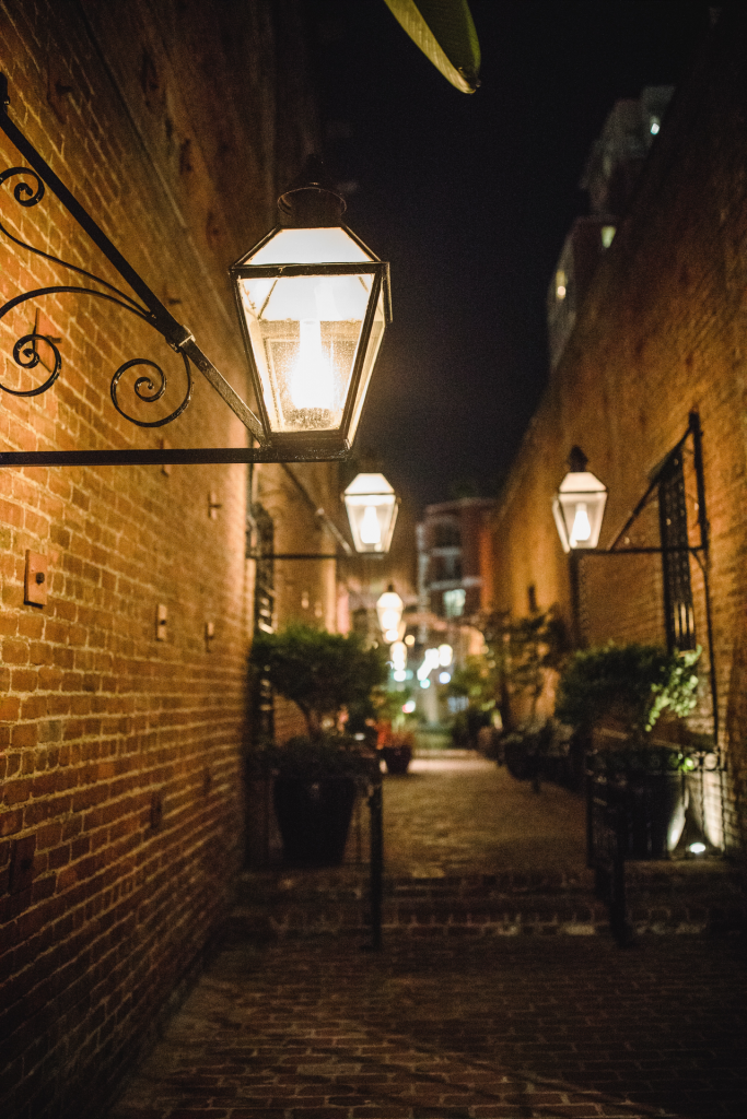 Multiple lit lamps in brick alley at night