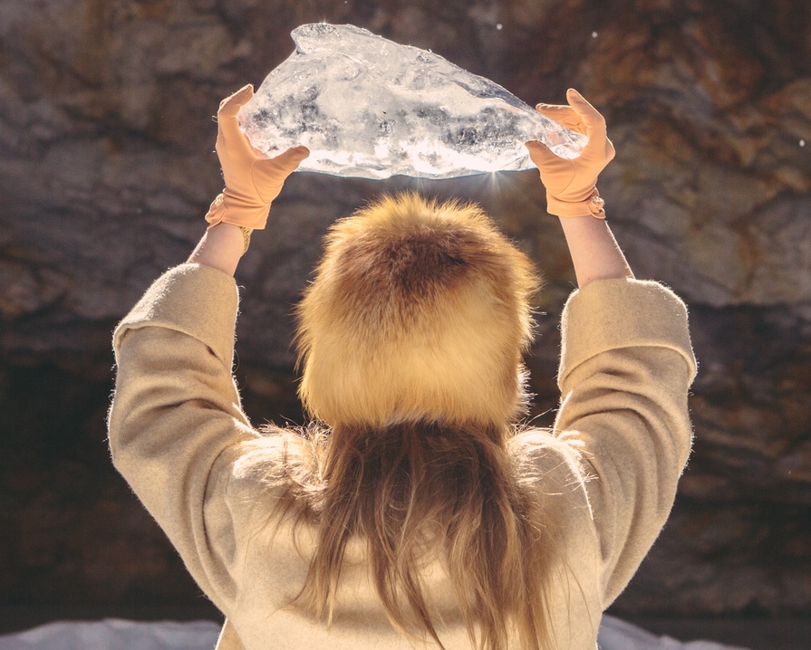 Woman holding up large chunk of ice up to the sunshine.