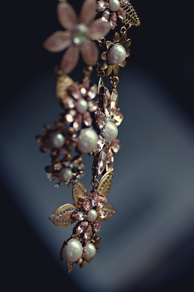 Dangling necklace of pearls, gold ornate flowers with light pink jewels.