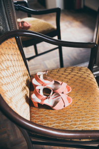 Close up image of orange sandals sitting on top of a brown/tan chair 