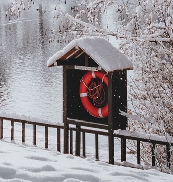 Red lifesaver next to a lake in winter