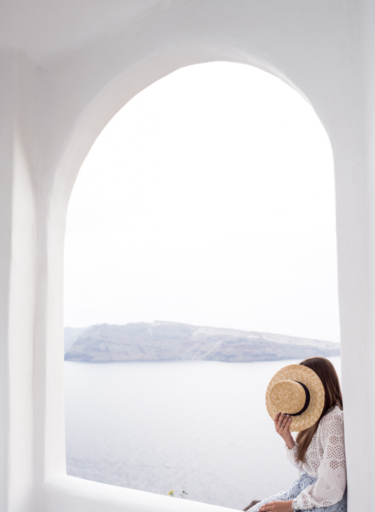 Girl holding hat sitting in alcove in Greece