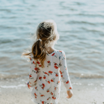 Little girl in floral dress looking at the beach