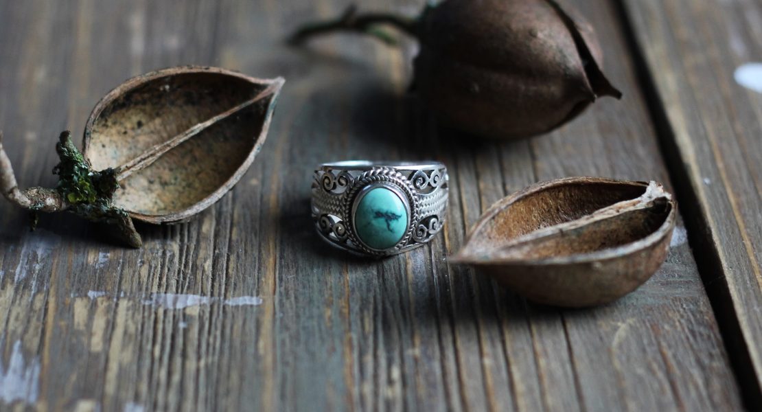 Turquoise stone, silver ring with nuts on top of wood table