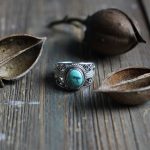 Turquoise silver ring and nuts on wood table 