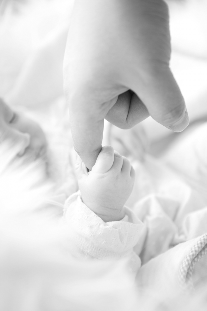 Close-up black and white image of baby holding parent's finger