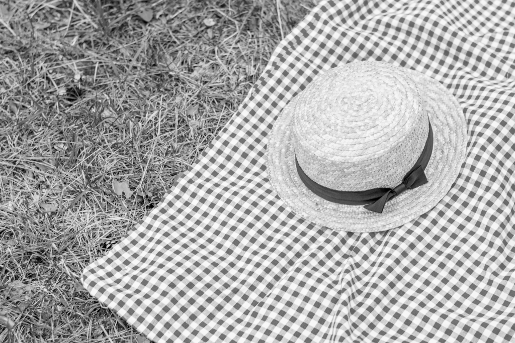 Black and white image of straw hat on checkered tablecloth