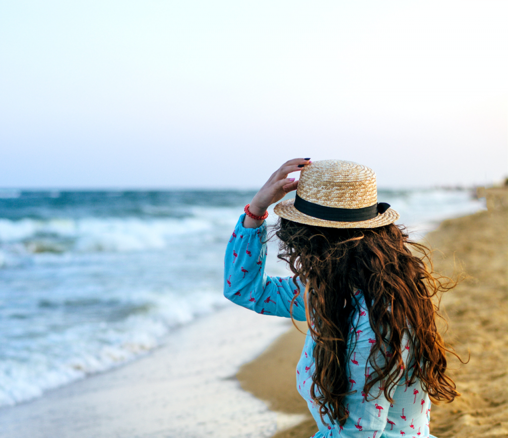 Girl with hat looking at ocean