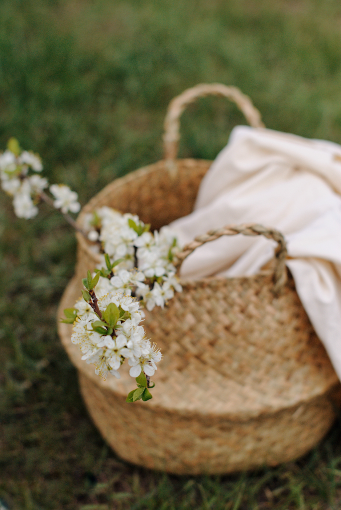 Basket with blanket and white flowers sitting on lawn