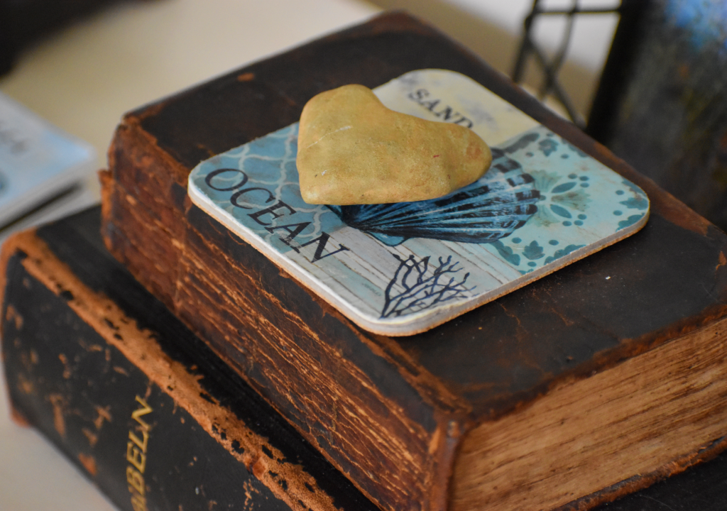 Heart rock on ocean coaster on two brown books