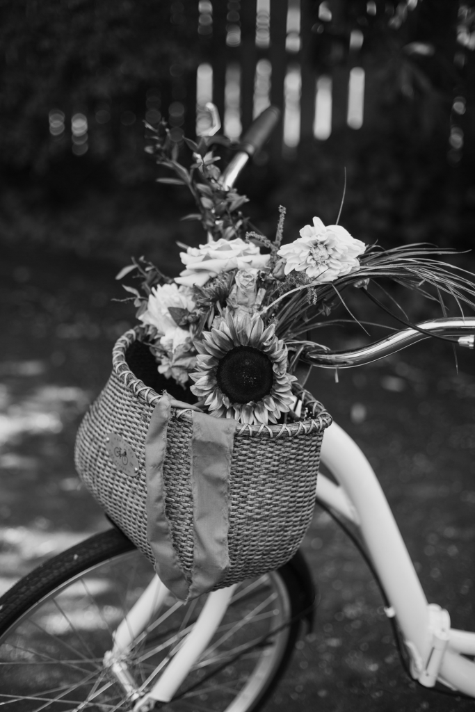 Black and white image of white bicycle with basket with flowers